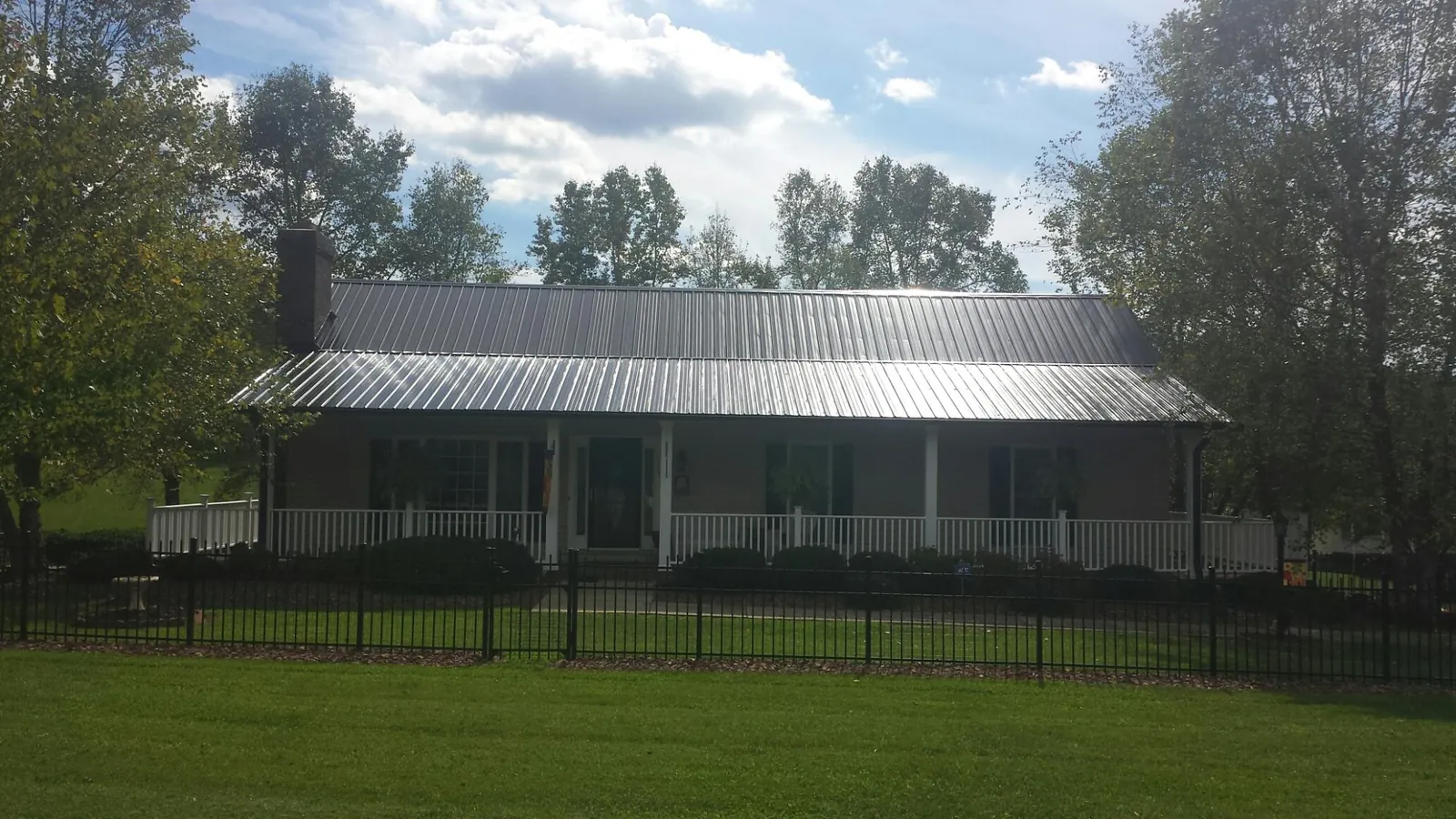 Gray metal roof on a brick ranch with a full width front porch — Gutter Guard Installation work by our crew in Harvard